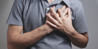 Mlad moški se drži z rokama za srce zaradi bolečine v prsih